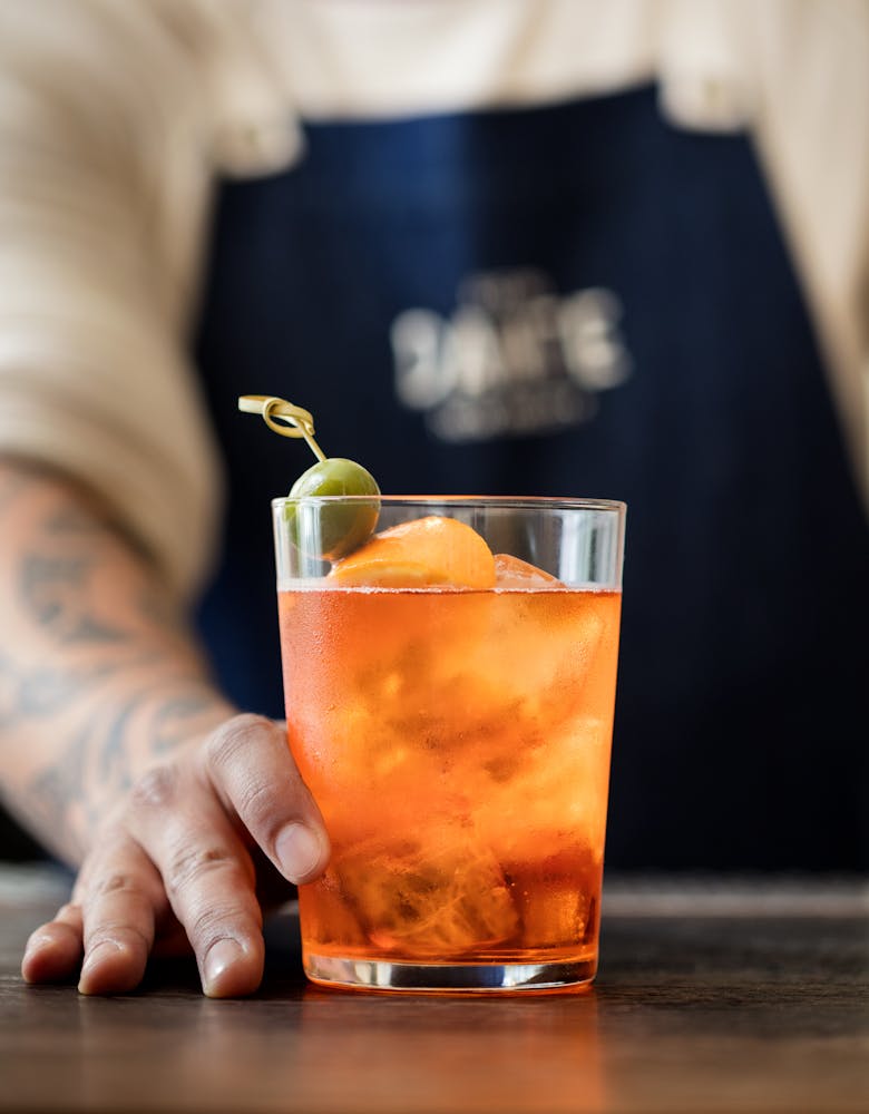 a hand holding a glass of aperol spritz