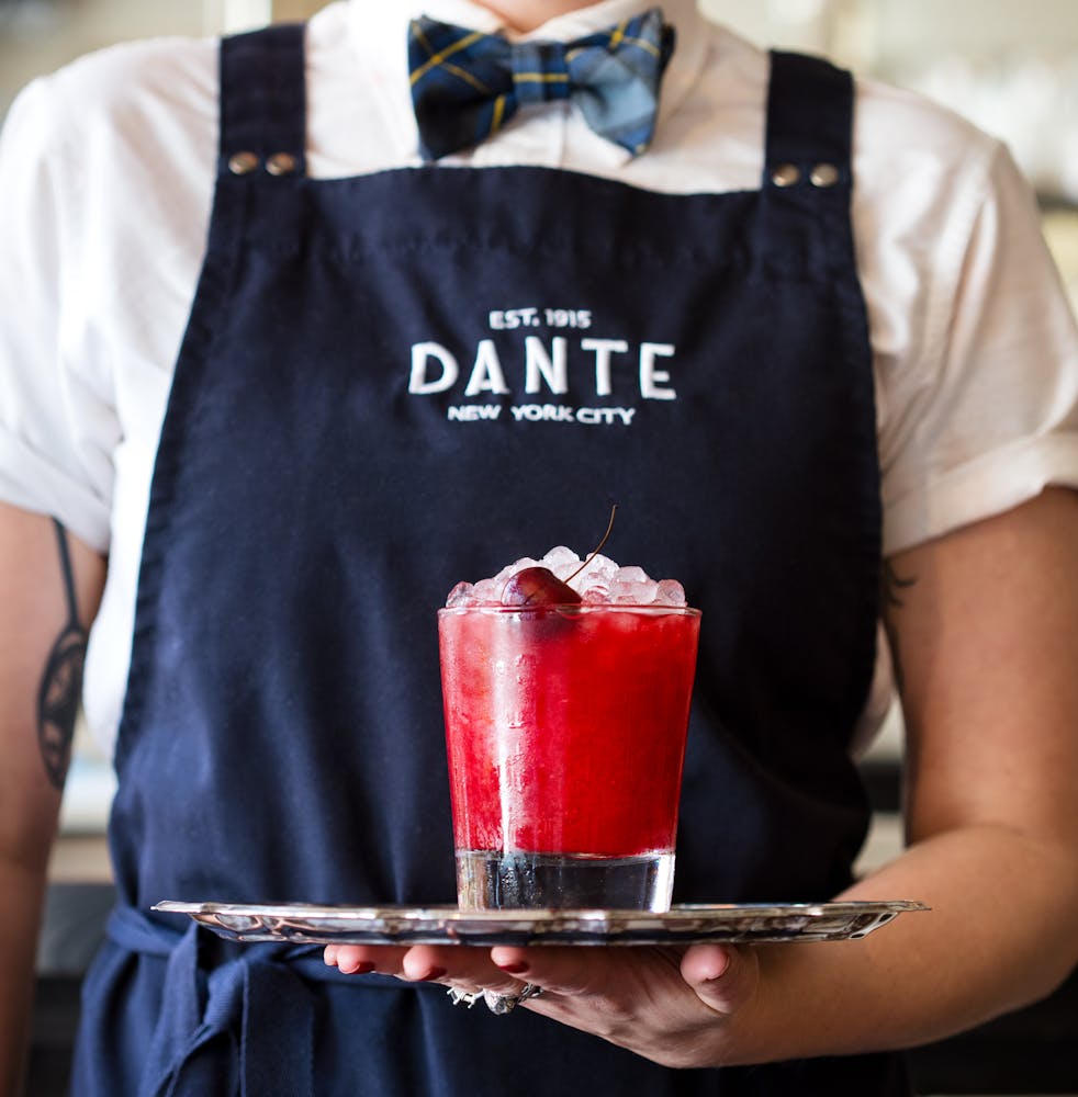 server with a tray and red drink